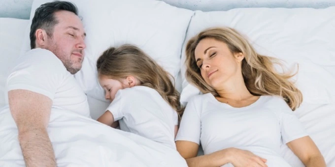 háromtagú család alszik az ágyban